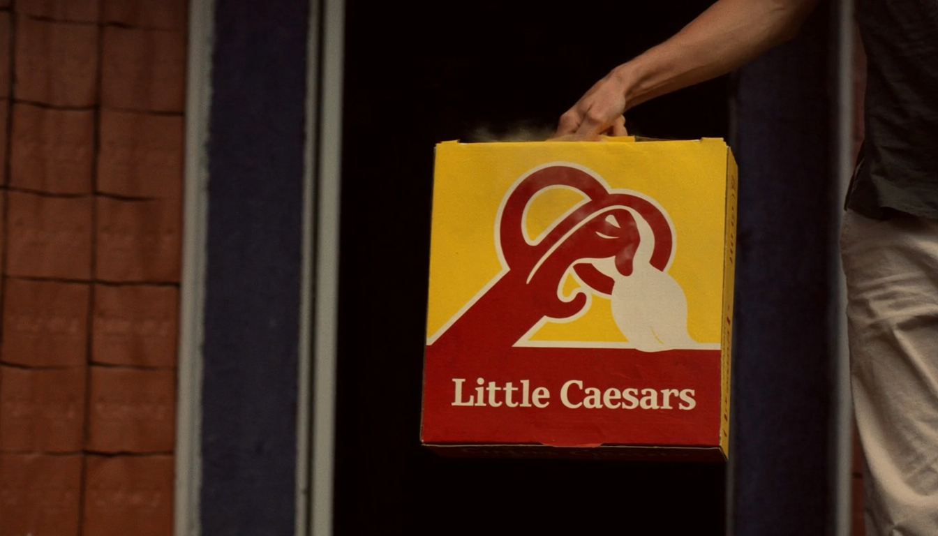 A dasher hand delivering a steaming Little Caesars pizza box at a doorstep